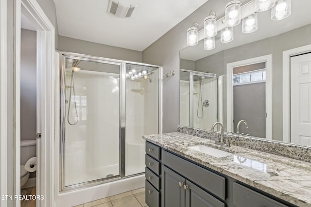 bathroom featuring tile patterned flooring, toilet, vanity, visible vents, and a shower stall