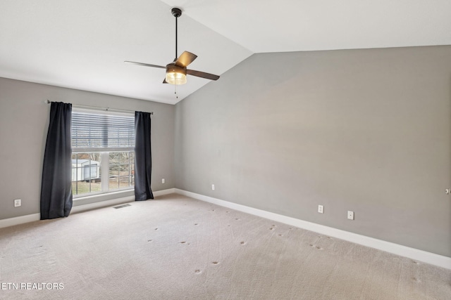 spare room featuring a ceiling fan, light colored carpet, vaulted ceiling, and baseboards