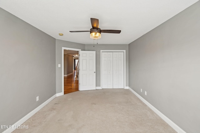 unfurnished bedroom featuring ceiling fan, baseboards, a closet, and light colored carpet