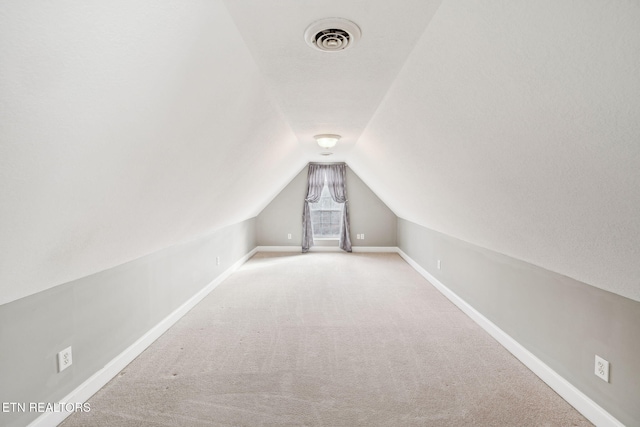 bonus room featuring lofted ceiling, light carpet, visible vents, and baseboards