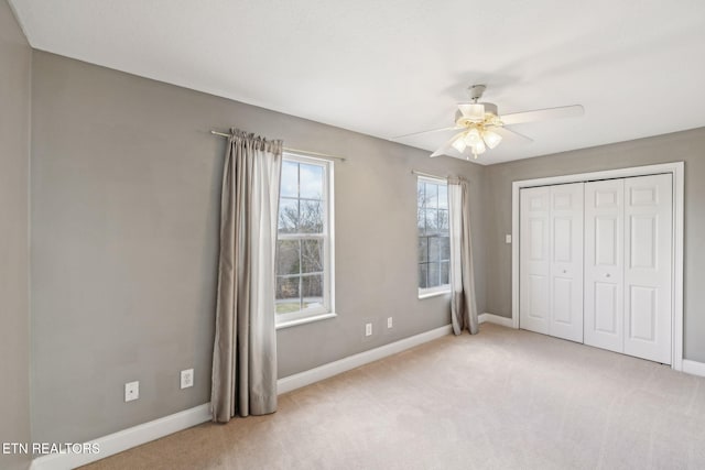 unfurnished bedroom with light carpet, a closet, and baseboards