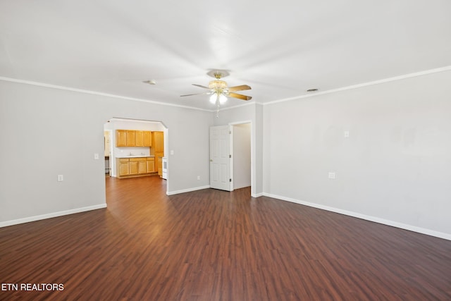 empty room featuring baseboards, arched walkways, dark wood-type flooring, and crown molding