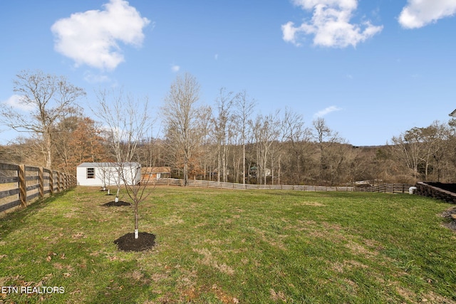 view of yard featuring a shed, a rural view, an outdoor structure, and fence