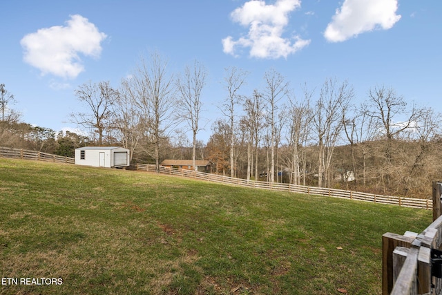 view of yard with a rural view, fence, and an outdoor structure
