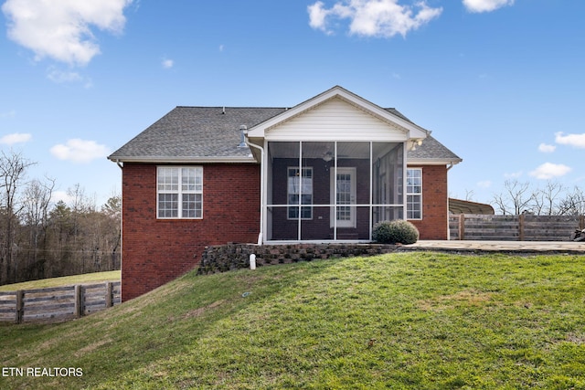 rear view of house with a sunroom, fence, a lawn, and brick siding