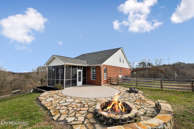 back of house featuring brick siding, a sunroom, a patio area, a fenced backyard, and a fire pit