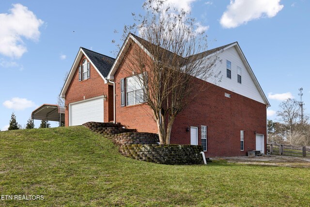 view of side of property with a garage, brick siding, and a lawn