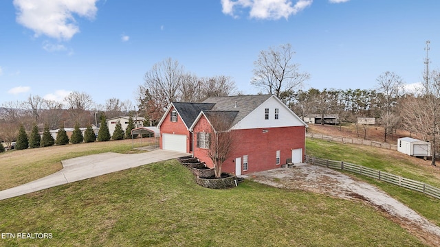 view of home's exterior with driveway, a garage, a yard, fence, and an outdoor structure
