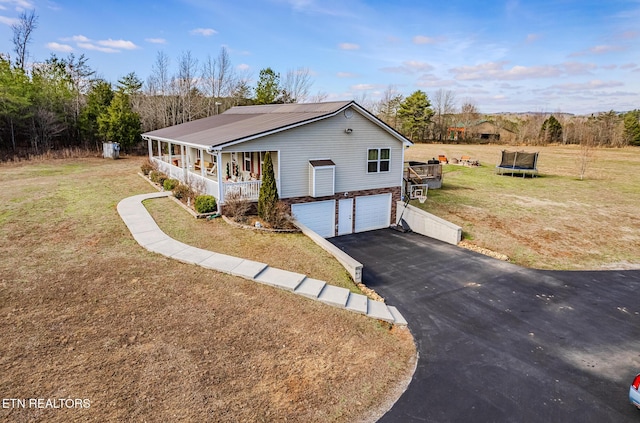 view of home's exterior with covered porch, a garage, a trampoline, and a yard