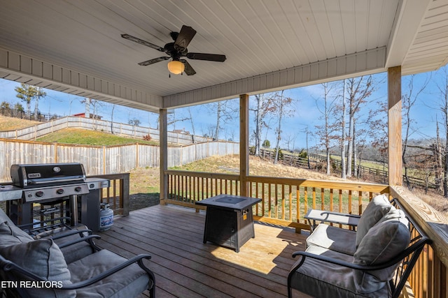 wooden terrace featuring ceiling fan, area for grilling, and a fire pit