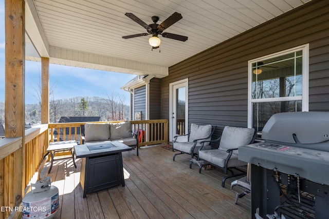 wooden terrace with ceiling fan, a mountain view, a grill, and an outdoor living space