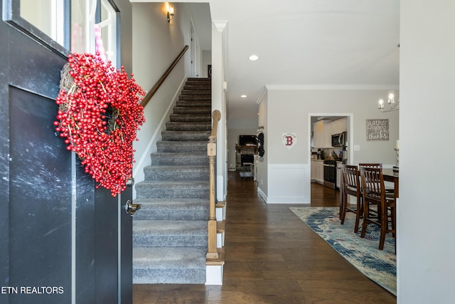 staircase featuring hardwood / wood-style floors, a chandelier, and crown molding