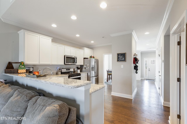 kitchen featuring dark wood-type flooring, white cabinetry, stainless steel appliances, kitchen peninsula, and a kitchen bar