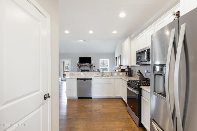 kitchen with appliances with stainless steel finishes, dark wood-type flooring, white cabinetry, light stone counters, and sink