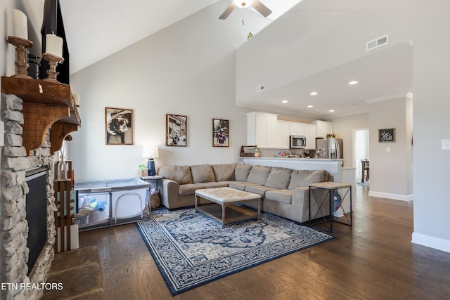 living room with high vaulted ceiling, ornamental molding, a stone fireplace, and dark hardwood / wood-style floors