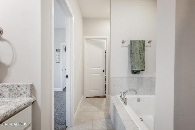 bathroom with tile patterned floors, a relaxing tiled tub, and vanity