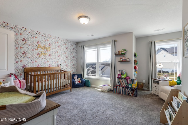 bedroom featuring a crib, a textured ceiling, and carpet