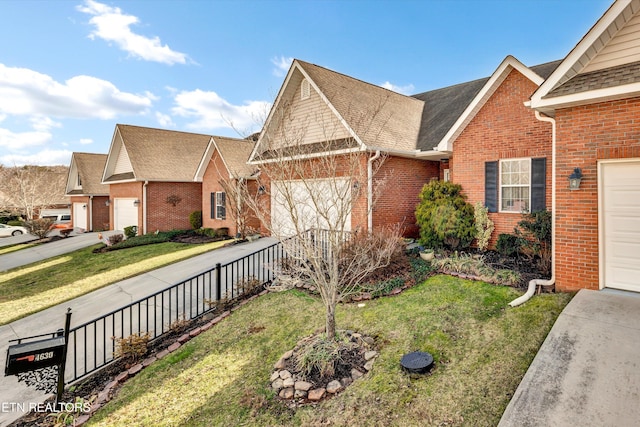 view of front of house featuring brick siding, concrete driveway, an attached garage, a front yard, and fence