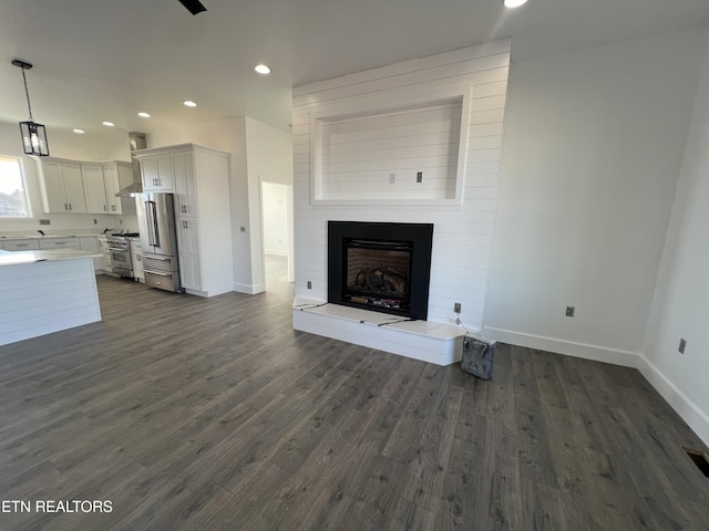 unfurnished living room with a large fireplace and dark hardwood / wood-style flooring