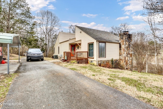 view of side of property featuring a chimney, aphalt driveway, and central AC