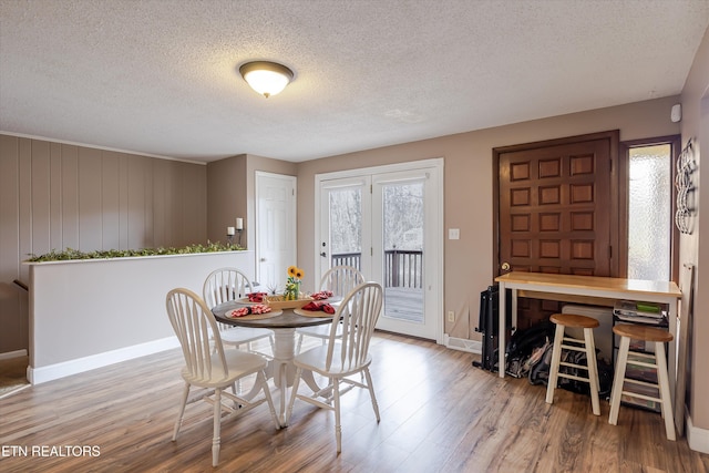 dining space featuring a textured ceiling, baseboards, and wood finished floors