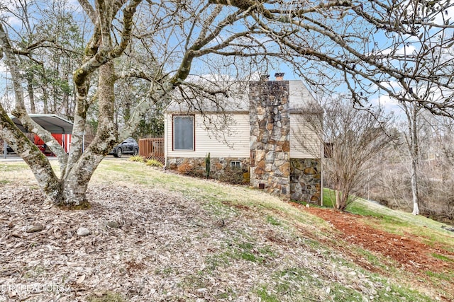 view of side of property with driveway, a yard, and a chimney