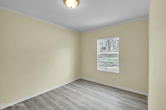 unfurnished room featuring light wood-type flooring, crown molding, and a textured ceiling