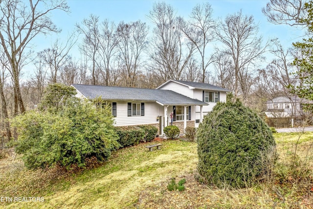 tri-level home with stone siding and a front yard