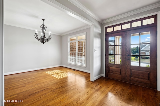 entrance foyer with light wood-type flooring, ornamental molding, french doors, and a notable chandelier