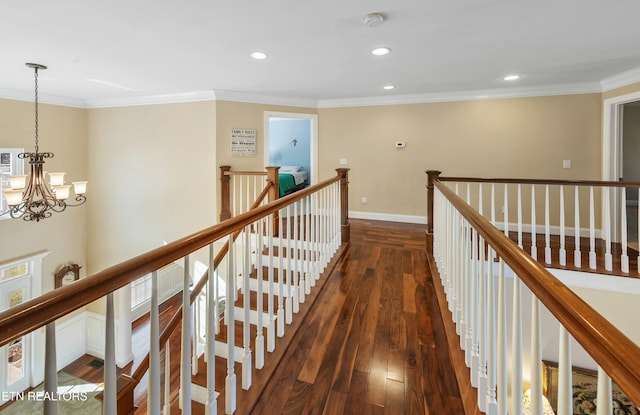 hallway with dark wood-style floors, an inviting chandelier, an upstairs landing, and crown molding