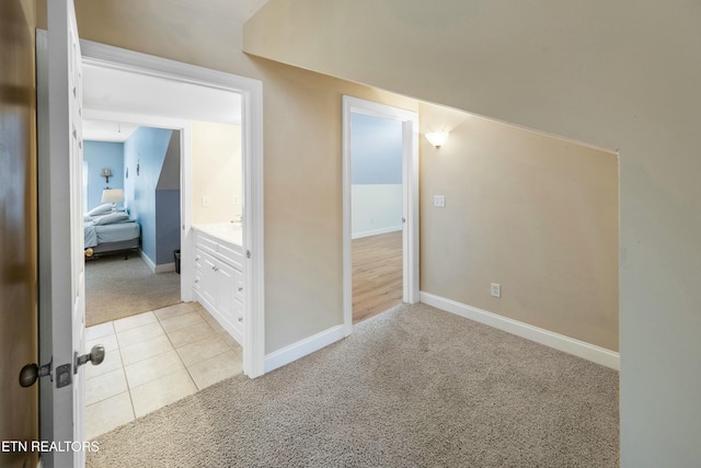 interior space featuring light carpet, light tile patterned floors, and baseboards