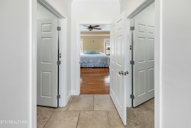 hall with ornamental molding and light tile patterned flooring