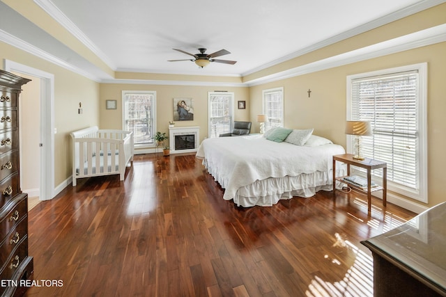 bedroom featuring crown molding, dark wood-style flooring, a fireplace, and baseboards