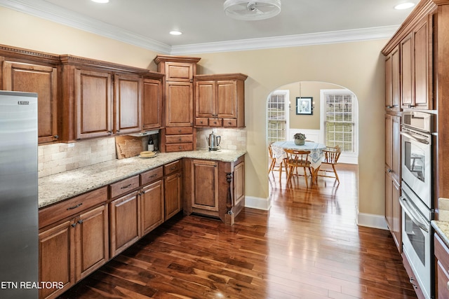 kitchen with appliances with stainless steel finishes, arched walkways, and brown cabinets