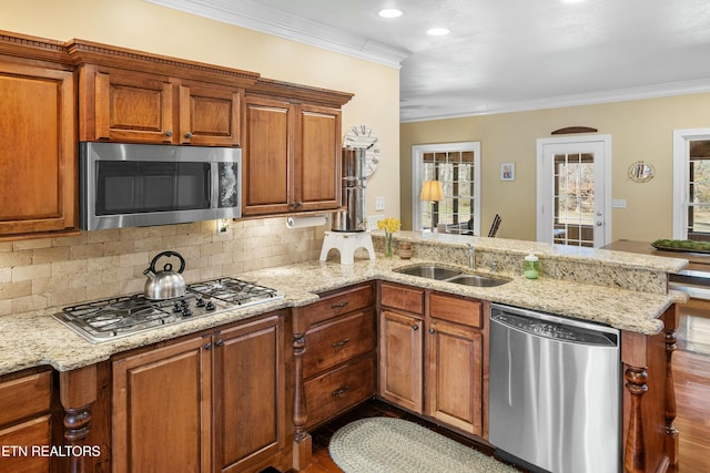 kitchen with crown molding, tasteful backsplash, appliances with stainless steel finishes, a sink, and a peninsula