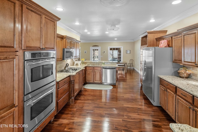 kitchen featuring stainless steel appliances, a peninsula, brown cabinets, light stone countertops, and crown molding