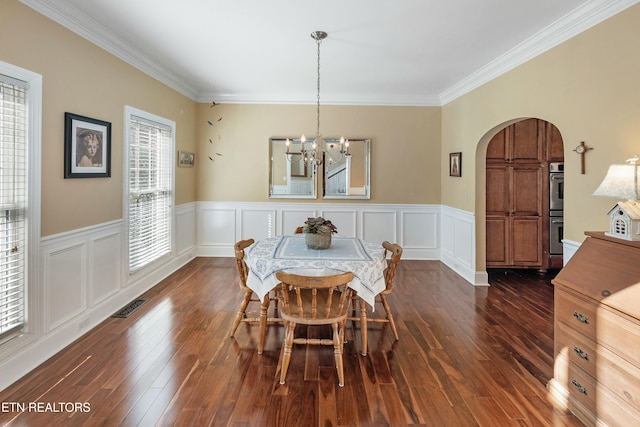 dining area with visible vents, arched walkways, a wainscoted wall, dark wood-style flooring, and a notable chandelier