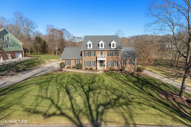 colonial house with a front yard, brick siding, and driveway