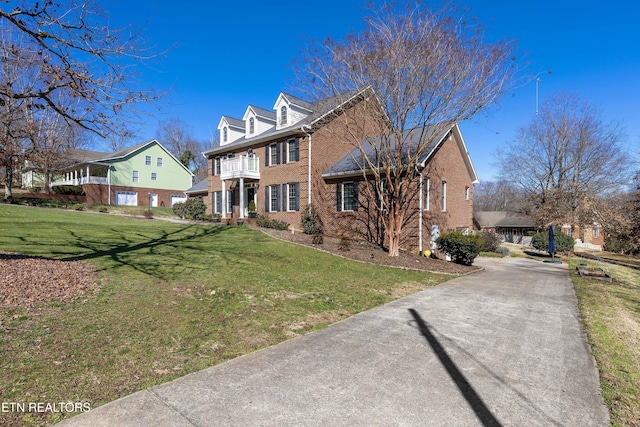 view of front of property with driveway, brick siding, a residential view, and a front yard