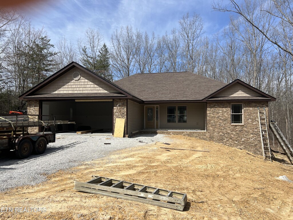 180 Hawes Cir, Crossville, TN 38558 - single story home with gravel driveway, an attached garage, brick siding, and roof with shingles
