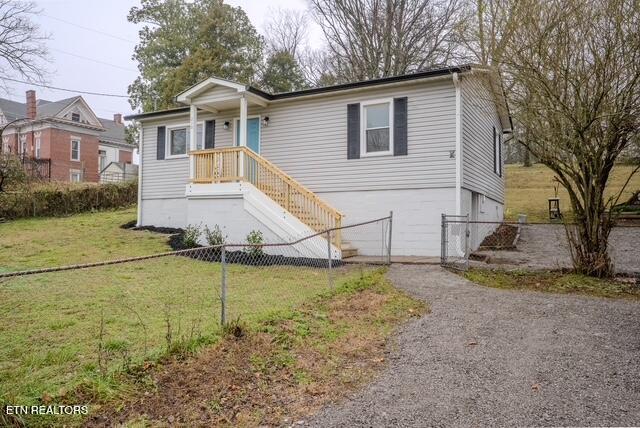 view of front of property featuring driveway, a garage, fence, and a front lawn