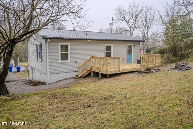 back of house with crawl space, a yard, a deck, and metal roof