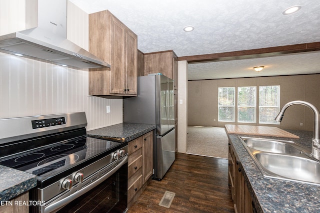 kitchen featuring sink, a textured ceiling, dark wood-type flooring, appliances with stainless steel finishes, and wall chimney exhaust hood