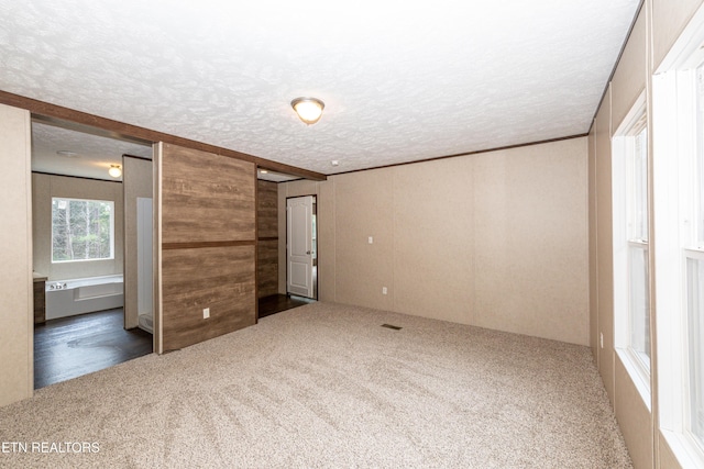 unfurnished bedroom with carpet flooring, wood walls, and a textured ceiling