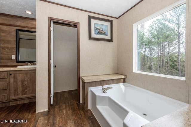 bathroom featuring hardwood / wood-style flooring, ornamental molding, vanity, and a bath