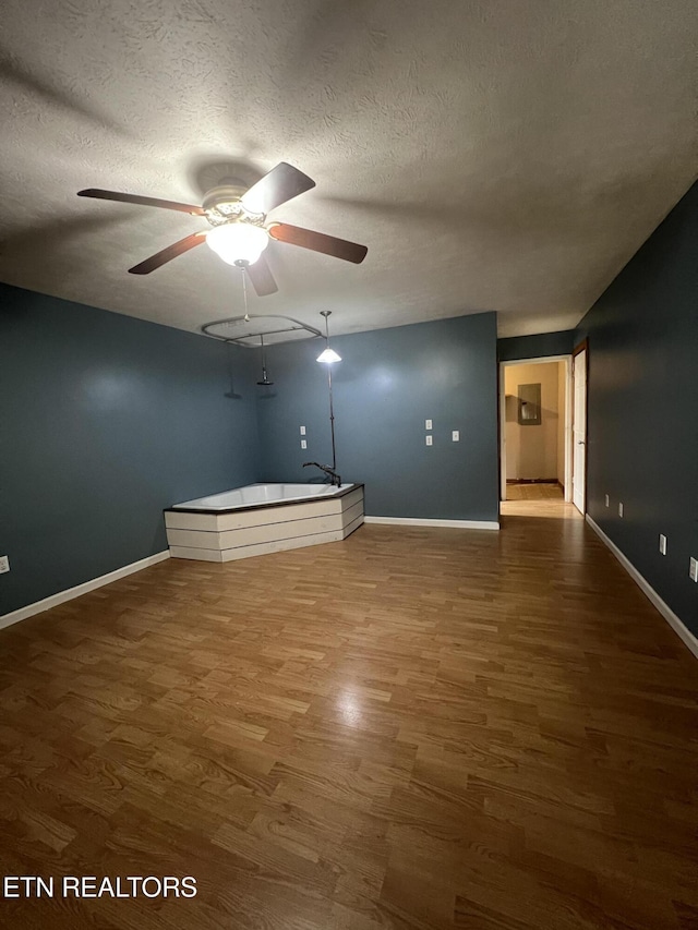 spare room with baseboards, a ceiling fan, wood finished floors, and a textured ceiling