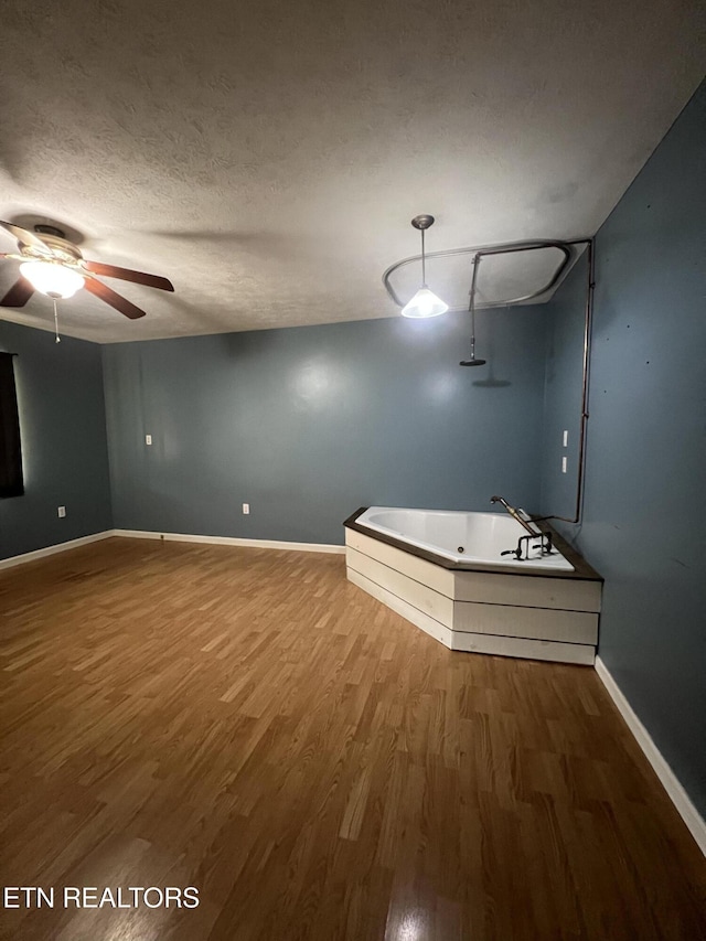 unfurnished room with baseboards, wood finished floors, a textured ceiling, and ceiling fan
