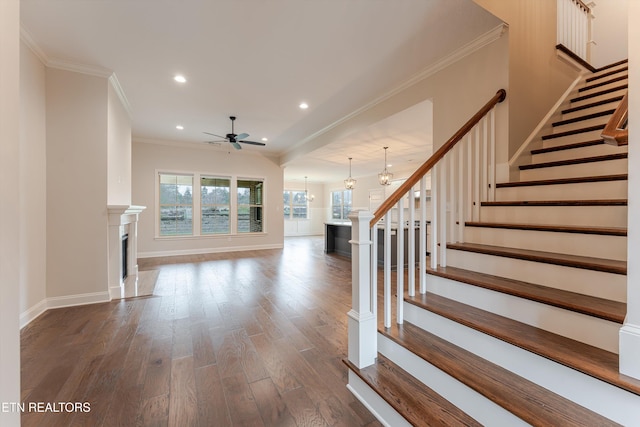 entryway featuring dark wood-style flooring, crown molding, a fireplace, baseboards, and stairs