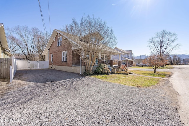 view of front of home featuring brick siding, covered porch, a gate, fence, and driveway