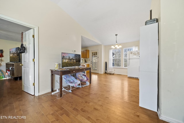 hall featuring baseboards, a notable chandelier, vaulted ceiling, and light wood finished floors